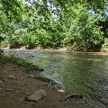 The South Fork of the Roanoke River flows past trees, rocks, and bare riverbank.